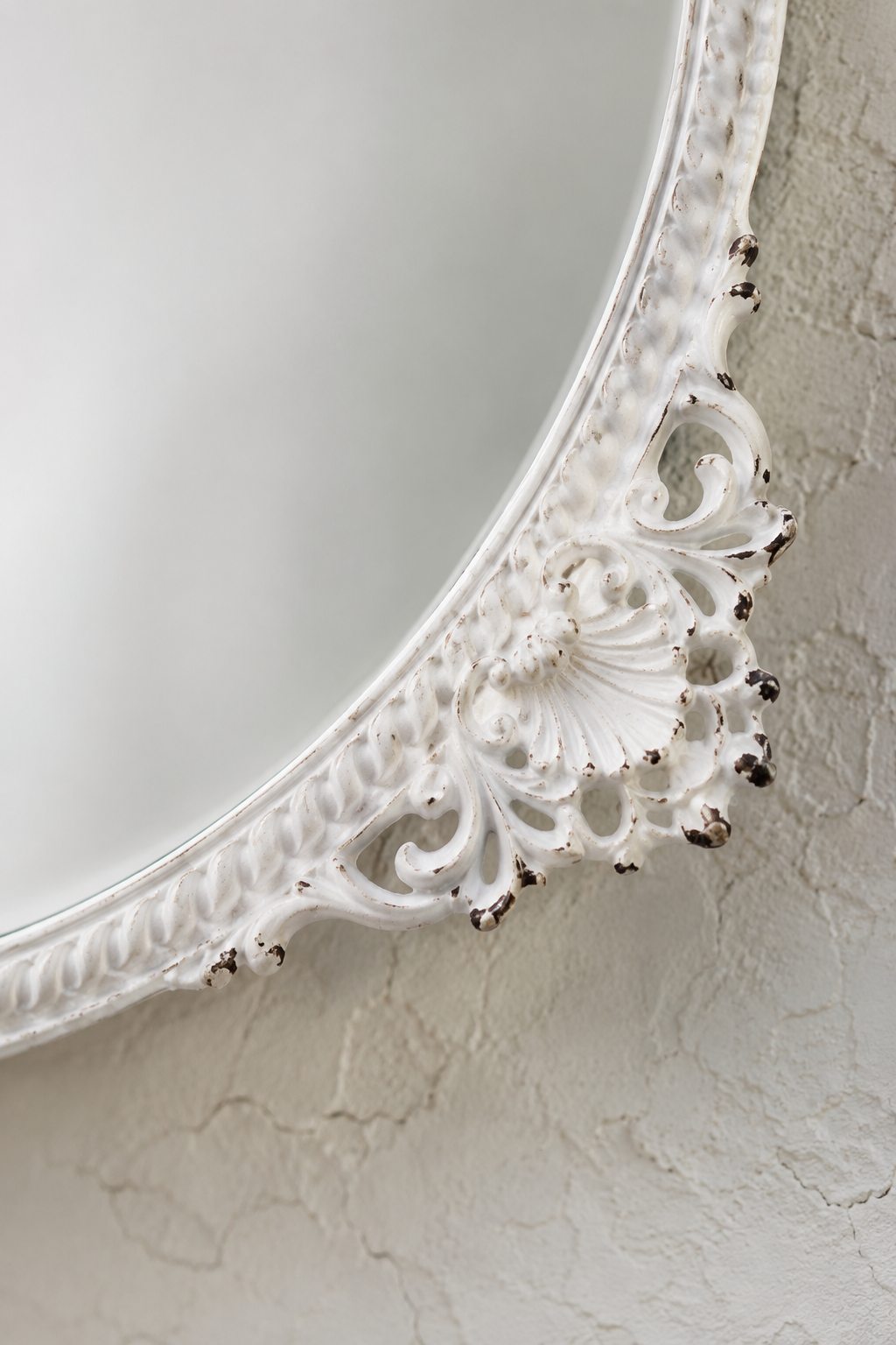 Détail macro de la ferronnerie blanc vieilli au bas du cadre de l'ovale baroque