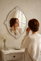Femme de dos près de l'ovale baroque blanc vieilli, coiffeuse en lumière du matin