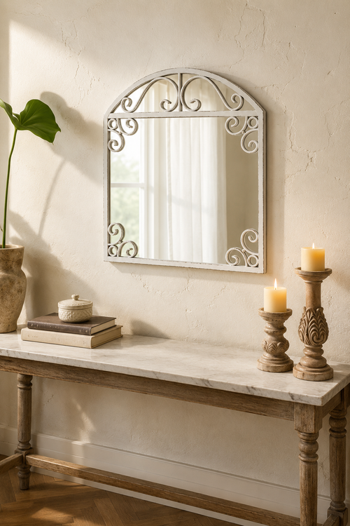 Arche à volutes blanc vieilli, ferronnerie sculptée, au-dessus d'une console au mur en plâtre