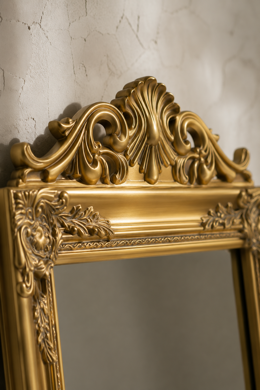 Détail macro du fronton en coquille sculptée et de la finition dorée de la psyché baroque