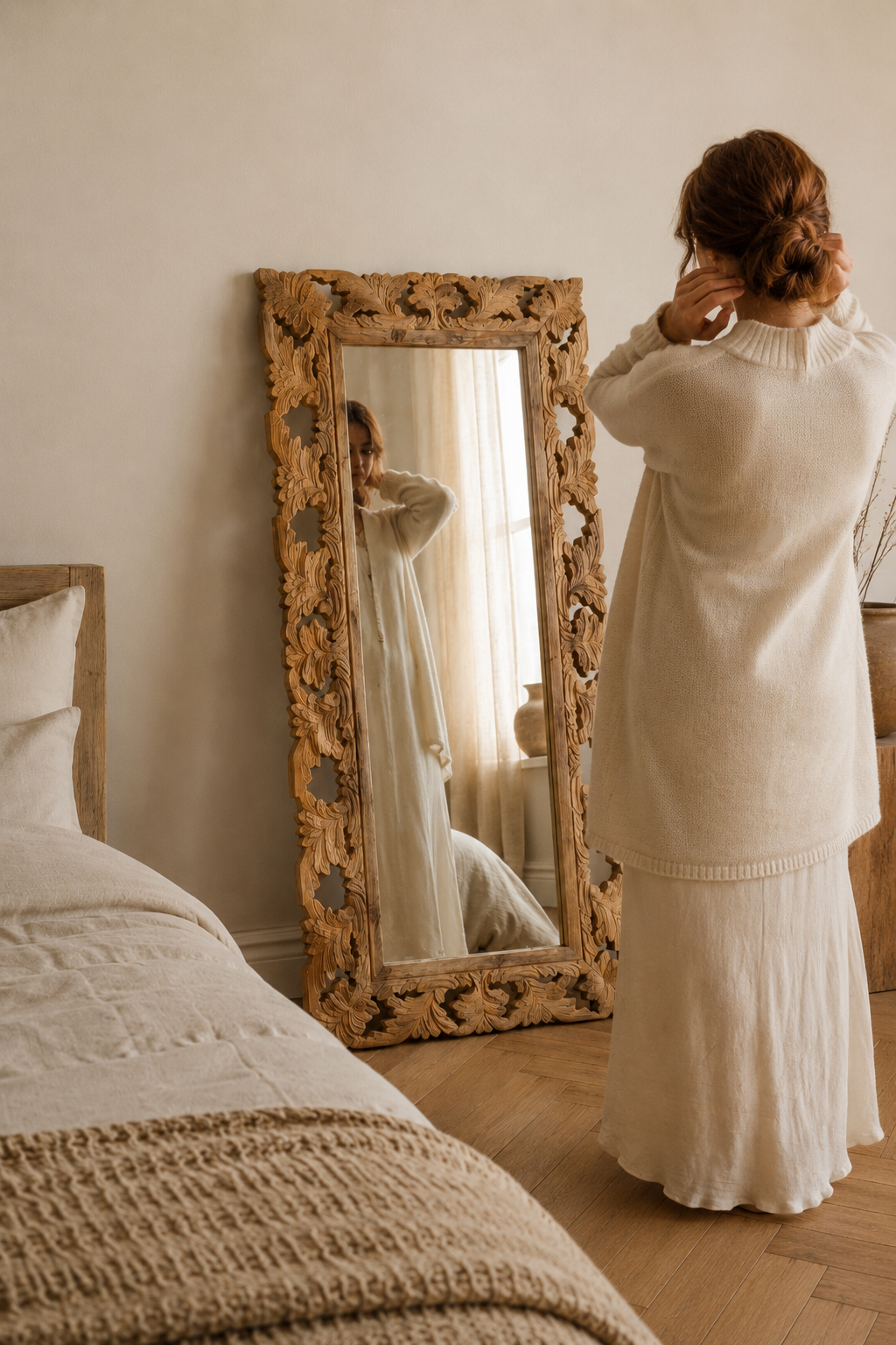 Miroir sculpté en bois de manguier 50x110 cm, Brut naturel, motif feuillage ajouré. En situation, présence humaine suggérée de dos.